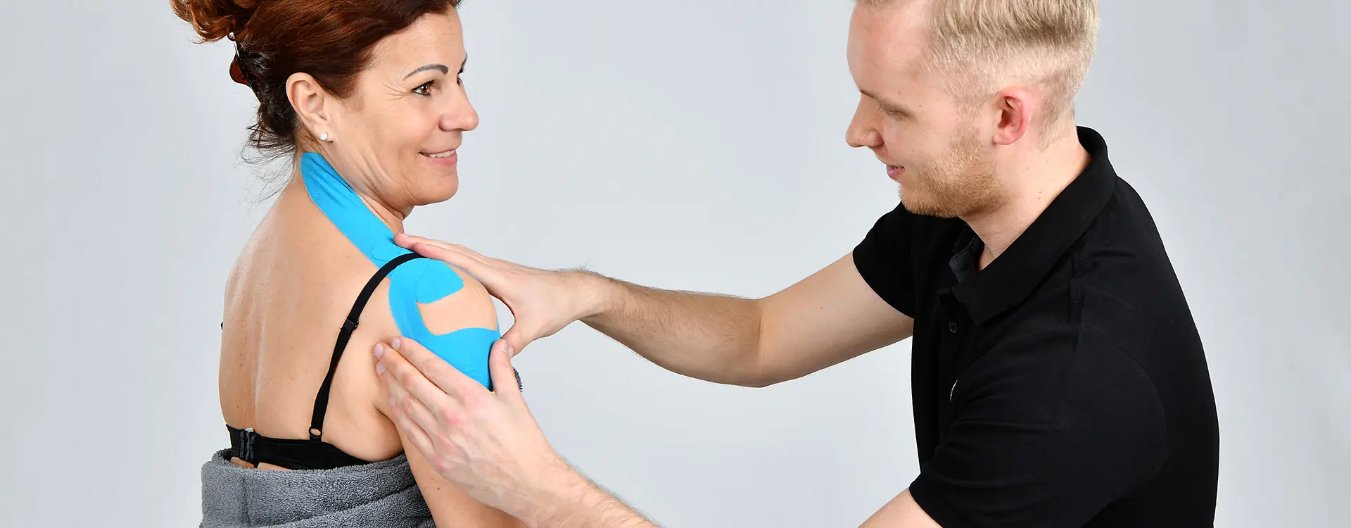 Kinesiotape wird an einer Schulter angebracht